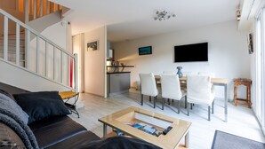A modern living room with a sofa, coffee table, and a dining area with chairs and a table. - Apartment 'Cap-ferret Phare Ref 130' with Private Terrace (Lège-Cap-Ferret)