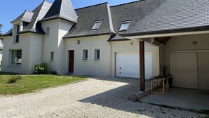 Ein zweistöckiges Haus mit Garage, einer überdachten Veranda und einem Kiesweg.