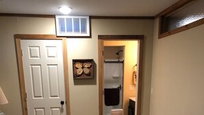 Une chambre à coucher avec un lit, une porte, une fenêtre et une salle de bain visible à travers une porte ouverte.