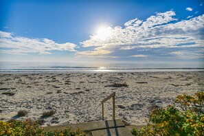 A beach with footprints, a flag, and a clear sky.