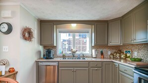 A kitchen with a dishwasher, a sink, and a window with a view of buildings. - Private access to the beach! Sleeps 9. (Wells)
