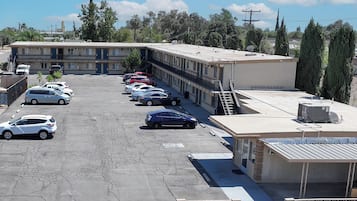 A parking lot with multiple cars, a building with a flat roof, and a satellite dish.
