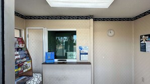A reception area with a counter, a clock, and a window.