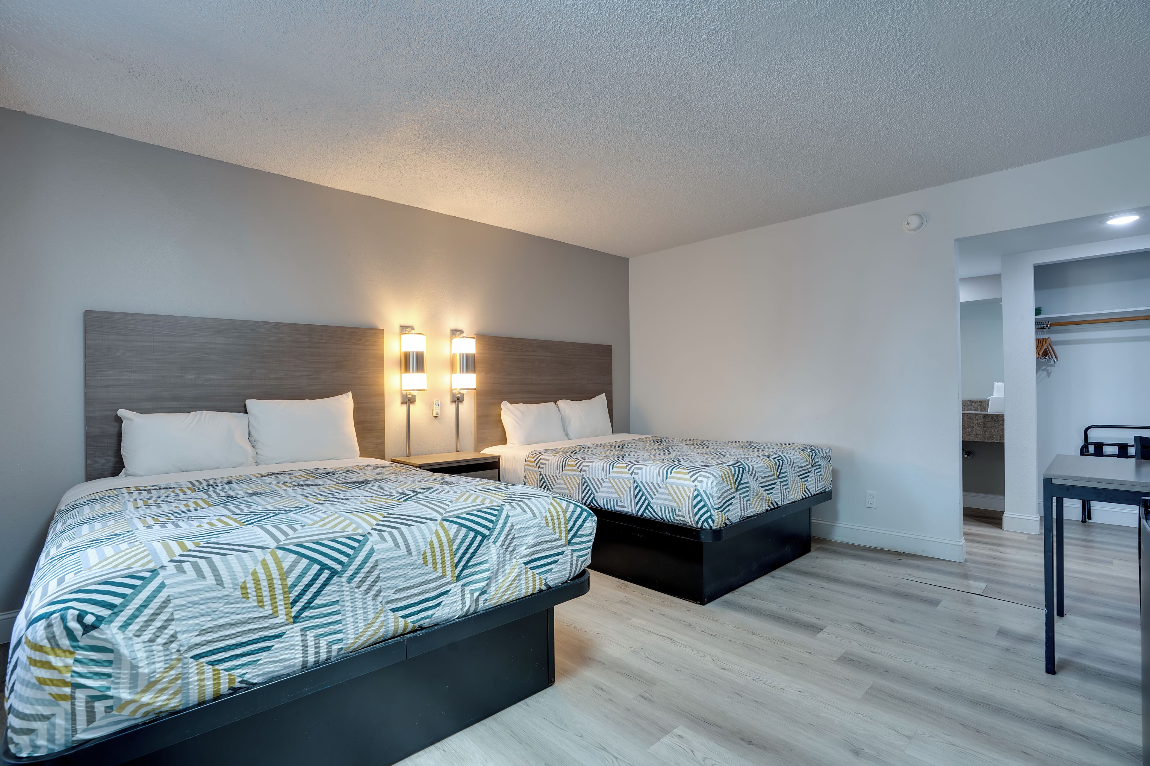 Habitación de hotel con dos camas, un escritorio y un armario.