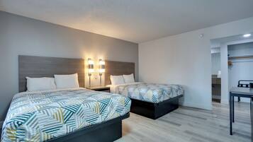 Habitación de hotel con dos camas, un escritorio y un armario.