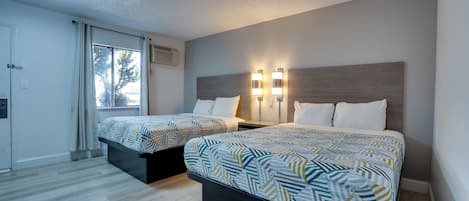 Habitación de hotel con dos camas, una ventana y una lámpara en el techo.