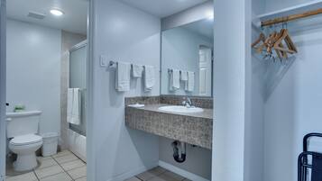 A bathroom with a toilet, sink, mirror, and towel rack.