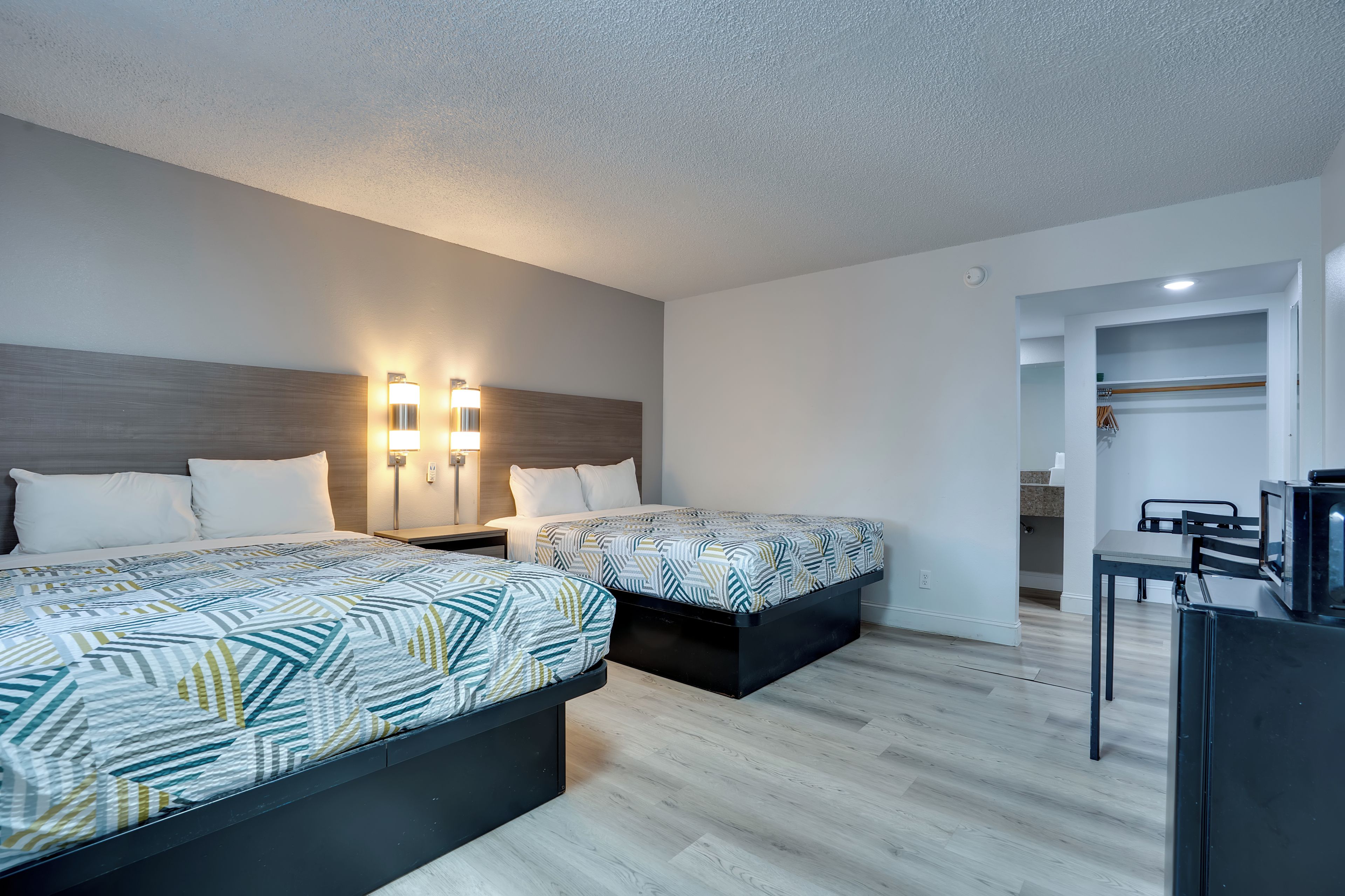 A hotel room with two beds, a desk, and a TV.