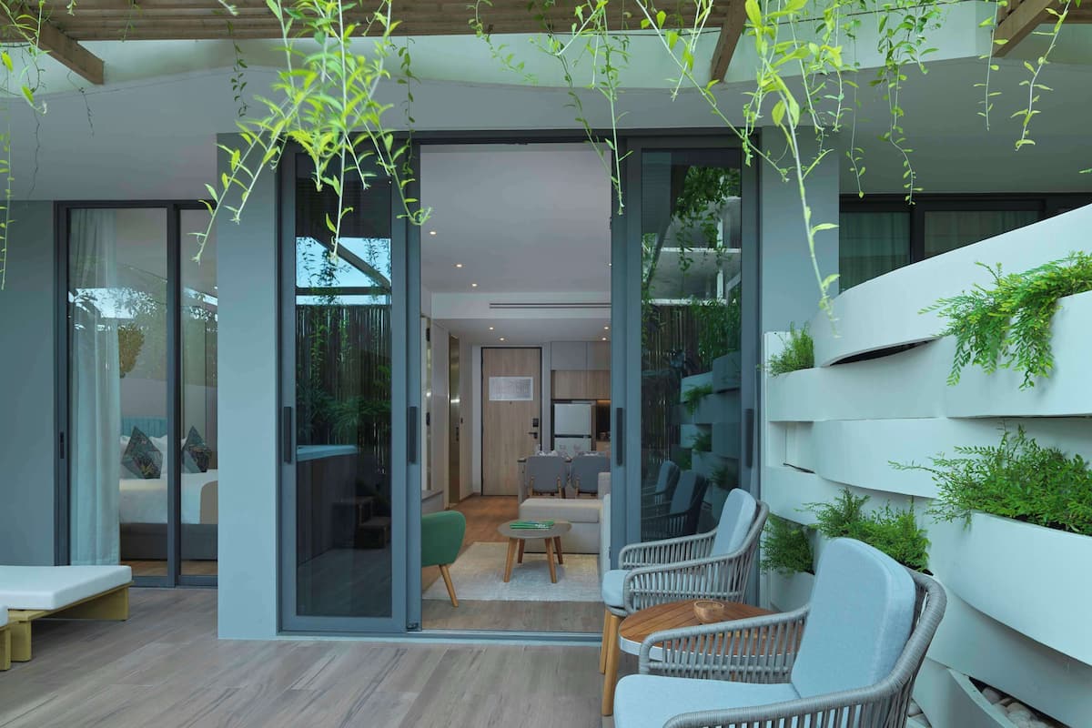 A modern interior with a seating area, a dining table, and a view through a glass door to a living room.