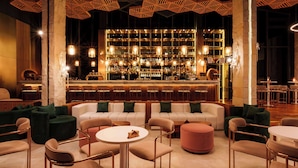 A bar area with a bar counter, shelves of bottles, and seating with round tables and chairs. - La Green Hotel & Residence (Choeng Thale)