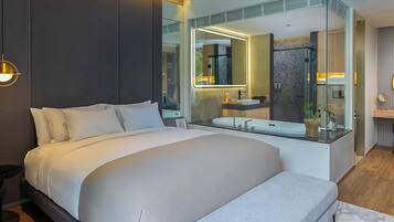 Una habitación de hotel moderna con una cama grande, un baño con paredes de vidrio y vistas a la ciudad.