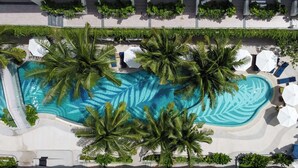 An aerial view of a resort with a large swimming pool surrounded by palm trees and lounge chairs. - La Green Hotel & Residence (Choeng Thale)