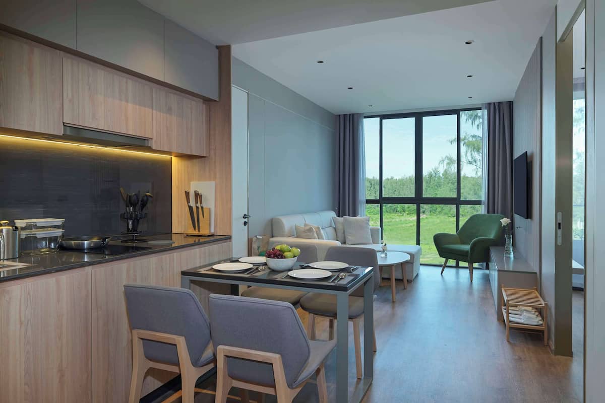 A modern kitchen with a dining area, a sofa, and a TV.