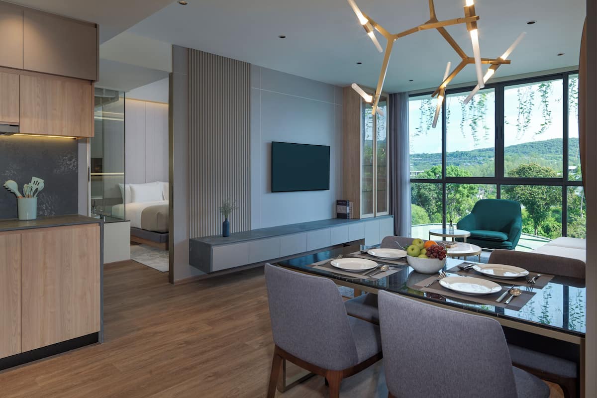 A modern kitchen with a dining area, large windows, and a view of the outdoors.