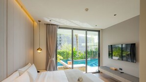 A modern hotel room with a large bed, a TV, and a view of a swimming pool and greenery. - La Green Hotel & Residence (Choeng Thale)