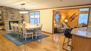 A spacious living area with a dining table, chairs, a fireplace, and a view of the outdoors. - Relaxing Lake Hamilton Home with Private Dock, Hot Tub, Kayaks, Fire Pit (Royal)