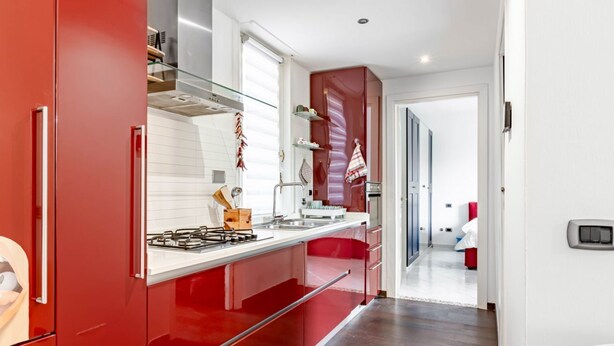 A modern kitchen with red cabinetry, a gas stove, and a stainless steel sink. - GuestHost - Modern apartment of about 55sqm, located on the first floor of a building with a lift (steps to access), can accommodate up to 2 people.The accommodation is located in a central district, served by all the main services: bars, restaurants, su (Cagliari)