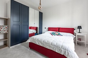 A bedroom with a bed, a wardrobe, a bedside table, and a hanging light fixture. - GuestHost - Modern apartment of about 55sqm, located on the first floor of a building with a lift (steps to access), can accommodate up to 2 people.The accommodation is located in a central district, served by all the main services: bars, restaurants, su (Cagliari)