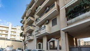 A multi-story residential building with balconies, air conditioning units, and a gated entrance. - GuestHost - Modern apartment of about 55sqm, located on the first floor of a building with a lift (steps to access), can accommodate up to 2 people.The accommodation is located in a central district, served by all the main services: bars, restaurants, su (Cagliari)