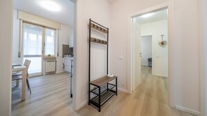 A hallway with a coat rack, a small table, and a door leading to another room.
