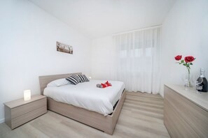 A modern bedroom with a bed, bedside table, and a nightstand.