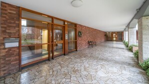 A covered outdoor area with stone flooring, wooden doors, and a bench.