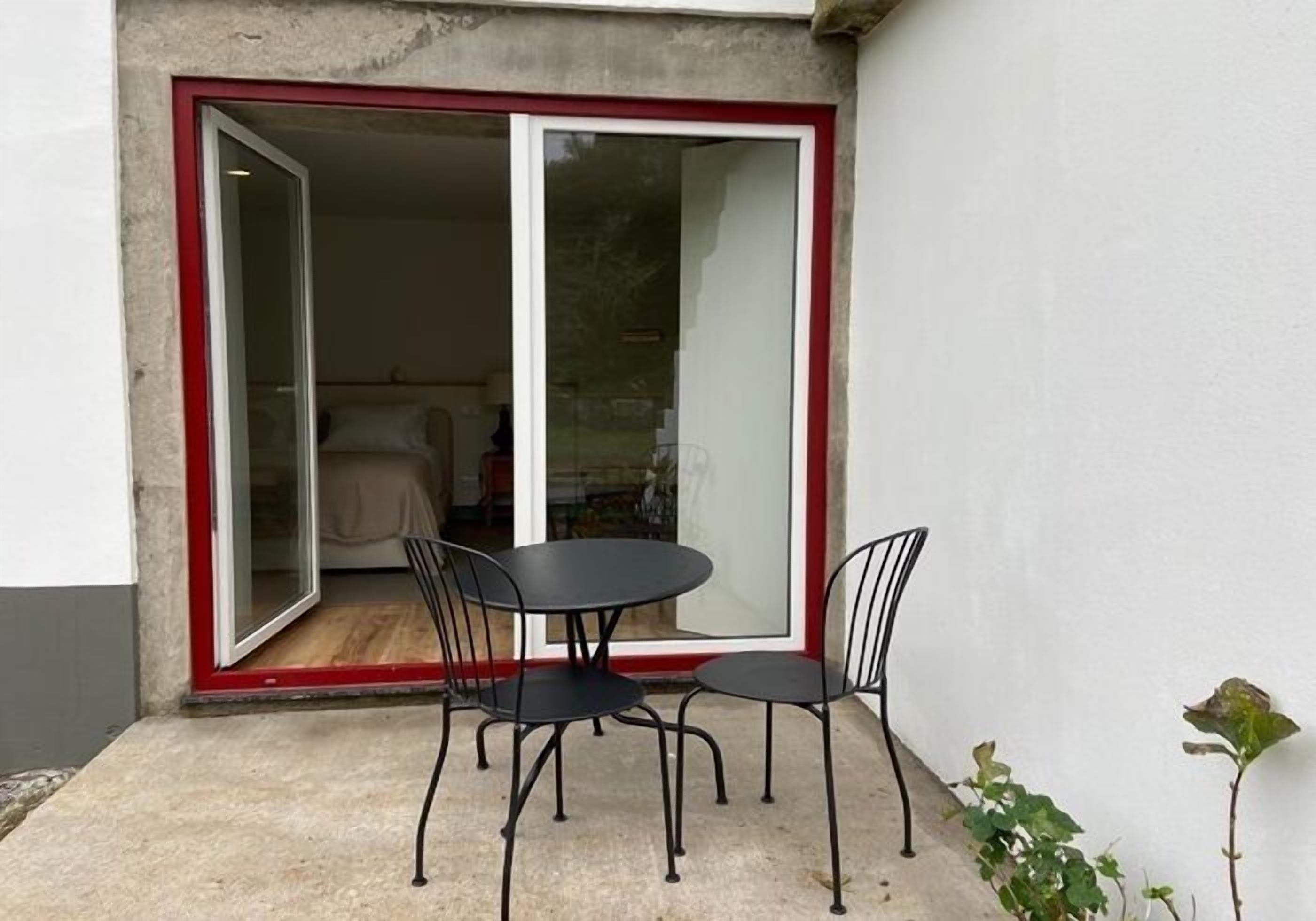 A small patio with a table and chairs, a sliding glass door, and a view into the interior of a room.