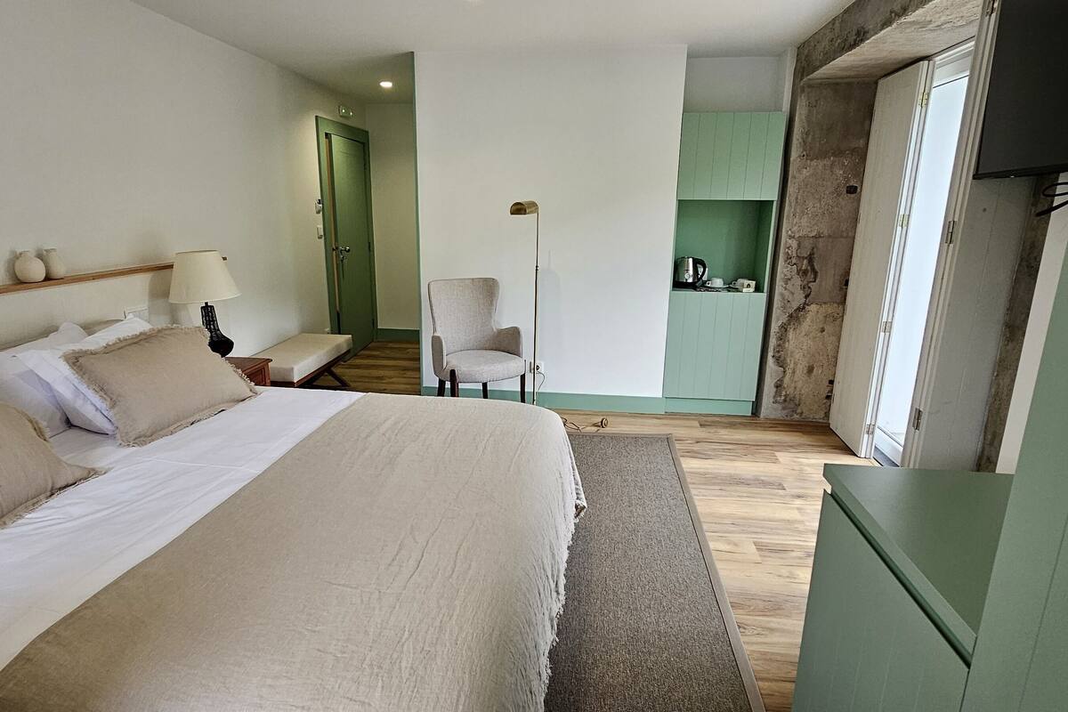 A bedroom with a large bed, bedside tables, a chair, and a green cabinet.