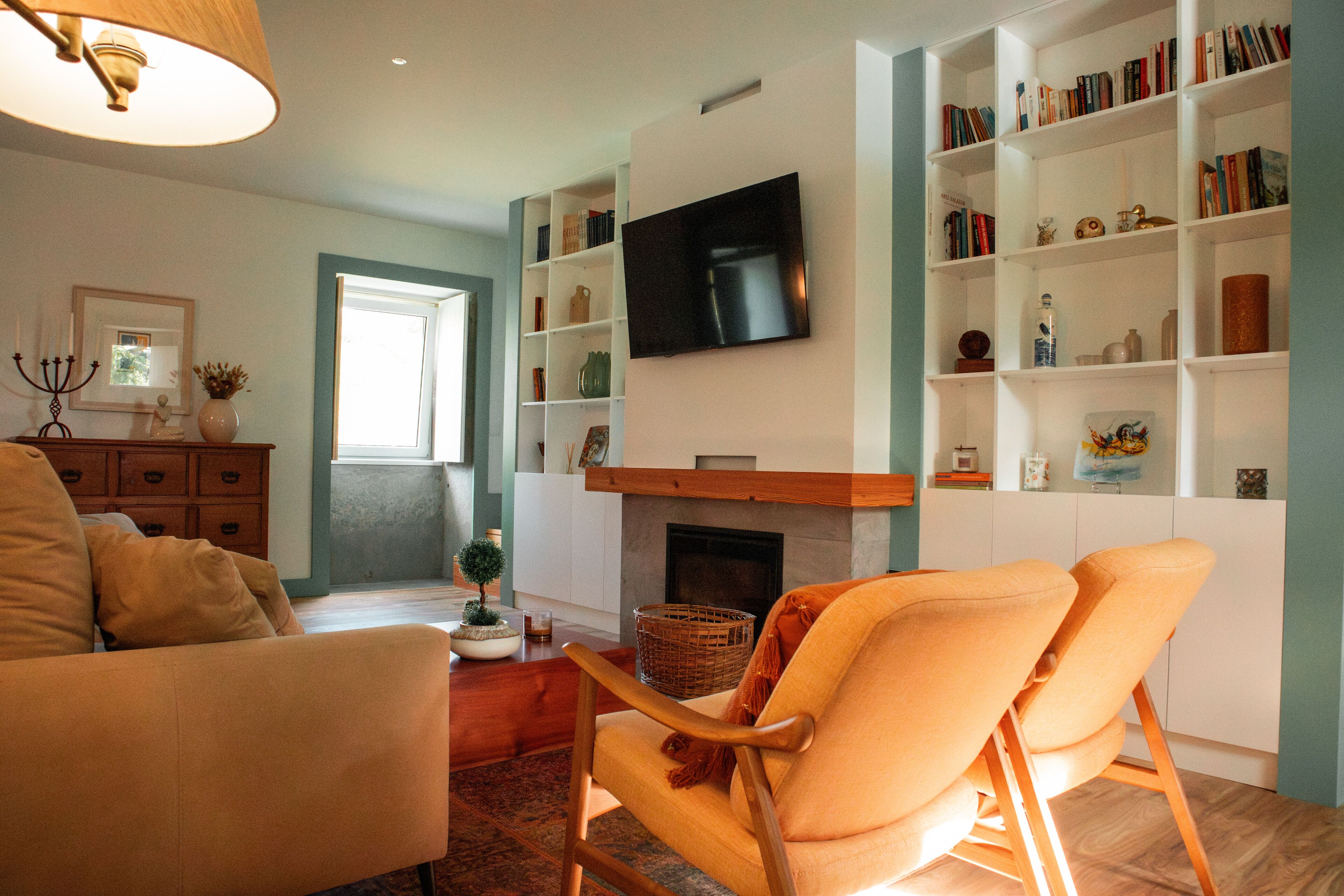 Ein Wohnzimmer mit Kamin, Bücherregalen, einem Fernseher und einer gemütlichen Sitzecke.