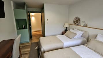 Habitación de hotel con dos camas, un escritorio, un televisor y un armario verde.