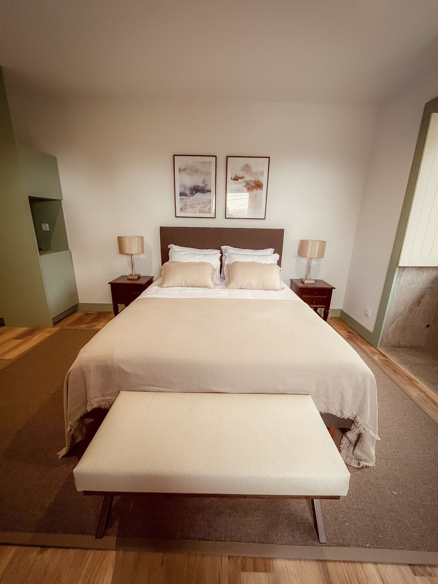 Ein ordentlich eingerichtetes Schlafzimmer mit einem großen Bett, zwei Nachttischen und einer Bank.