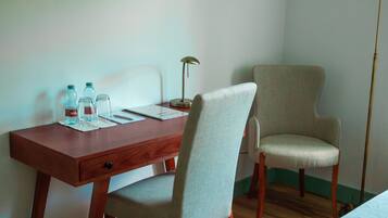 A wooden desk with a chair, a lamp, and a bottle of water.