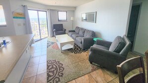 En moderne stue med sofa, lænestole, sofabord og et spiseområde med en bar.