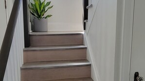 Eine Treppe mit einem Blumentopf am oberen Ende, die zu einer Tür mit einem runden Türknauf führt.