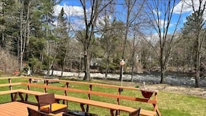 Eine Holzterrasse mit Korbmöbeln und einem hängenden Blumentopf.