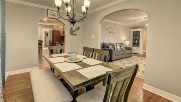 Un comedor con mesa de madera, bancos acolchados y un candelabro.