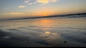 Una playa al atardecer con olas tranquilas y un cielo despejado.