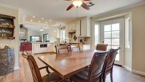 Una cocina amplia con una gran mesa de comedor, armarios blancos y un ventilador de techo.