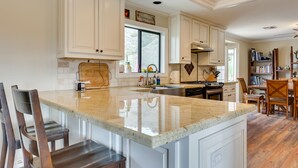 Una cocina amplia con armarios blancos, una isla grande y un comedor con sillas de madera.