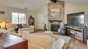 Una sala de estar con chimenea de piedra, un televisor de pantalla plana grande y un rincón de asientos acogedor con sofá y reposapiés.