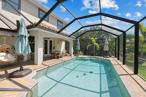 A covered swimming pool with a glass ceiling, surrounded by outdoor furniture and a house. - Tranquil Waterfront • 5th Ave&Beach 3mi • FastWiFi (Naples)