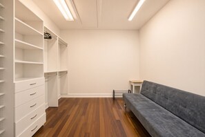 Um closet amplo com prateleiras abertas, gavetas e um sofá cinzento.