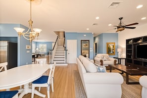 A modern living room with a staircase, a dining area, and a TV stand. - Tranquil Waterfront • 5th Ave&Beach 3mi • FastWiFi (Naples)