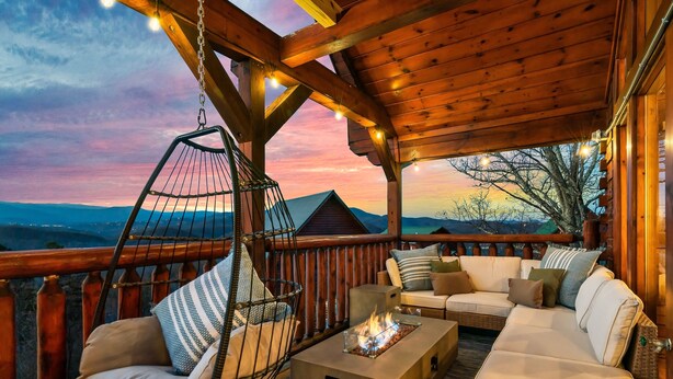 Eine Holzterrasse mit Hängesessel, Sofagarnitur und Feuerstelle.