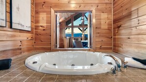 Eine Holzhütte mit einer großen Badewanne, Holzwänden und Blick durch eine Tür.