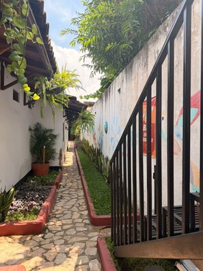 A narrow pathway flanked by walls with murals and potted plants. - Hotel Casa Nikté (Antigua Guatemala)