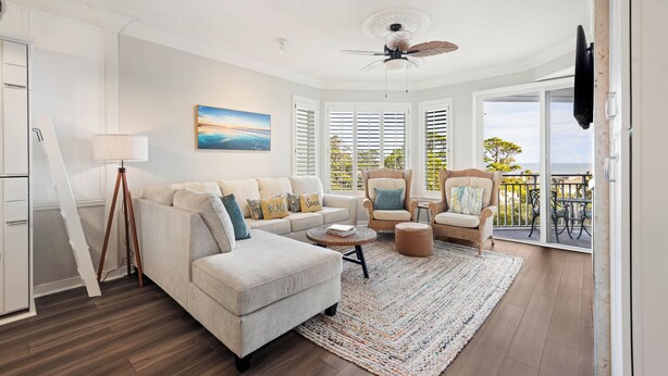 A modern living room with a sectional sofa, a round coffee table, and a ceiling fan. - SeaCrest ~N Forest Beach Coligny OCEANVIEW~HUGE 1 bedroom!  Top floor! POOL! Gym (Hilton Head Island)