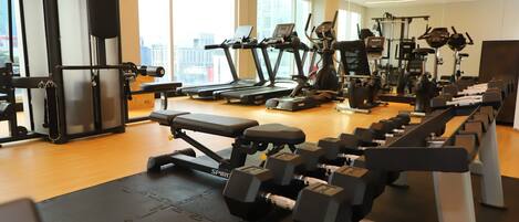 A gym with treadmills, dumbbells, and weight machines.