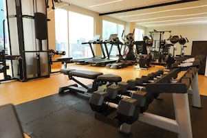 Un gimnasio con cintas de correr, mancuernas y máquinas de pesas.