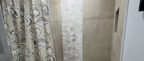 A bathroom with a shower, toilet, and a patterned shower curtain.
